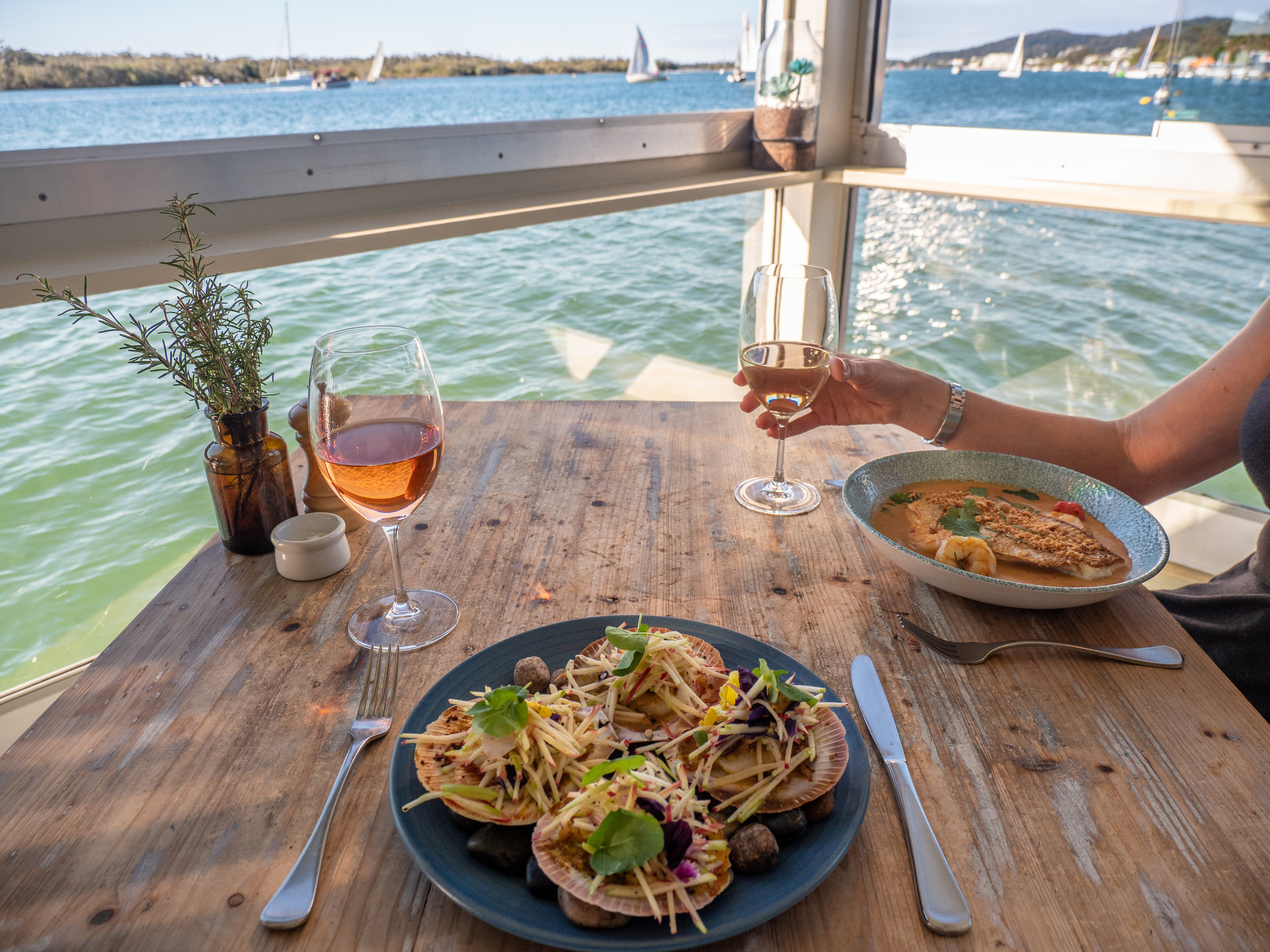 Couple dine on seafood and wine at a waterfront table at Noosa Boathouse